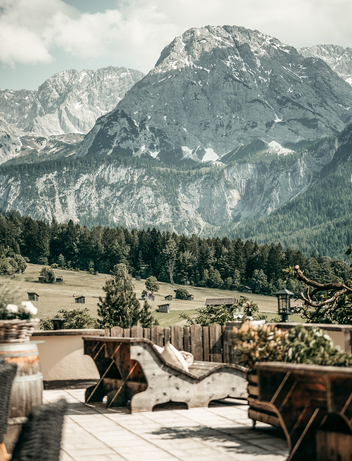 Terrasse mit Sitzgelegenheiten und Panoramablick auf eine alpine Berglandschaft.