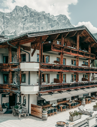 Traditionelles Alpenhotel mit Balkonen und Blick auf die umliegenden Berge.