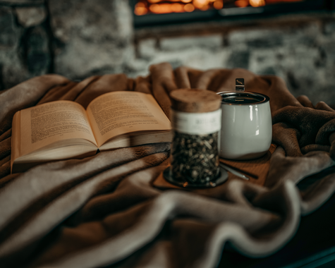 Gemütliche Winterstimmung mit offenem Buch, Kerze und warmem Getränk.