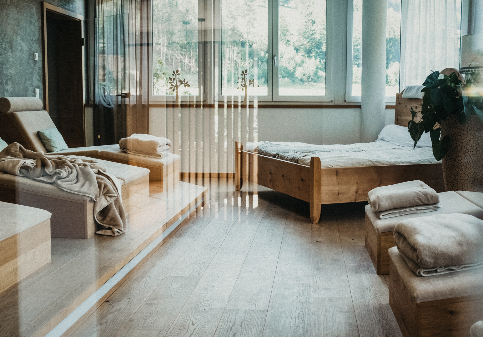 Ruhebereich mit Liegen und großen Fensterfronten im Wellnessbereich.