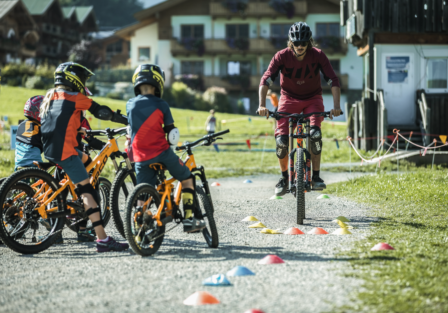 Jugendliche und Kinder fahren mit Fahrrädern auf einem Übungsparcours im Außenbereich einer Ferienanlage.
