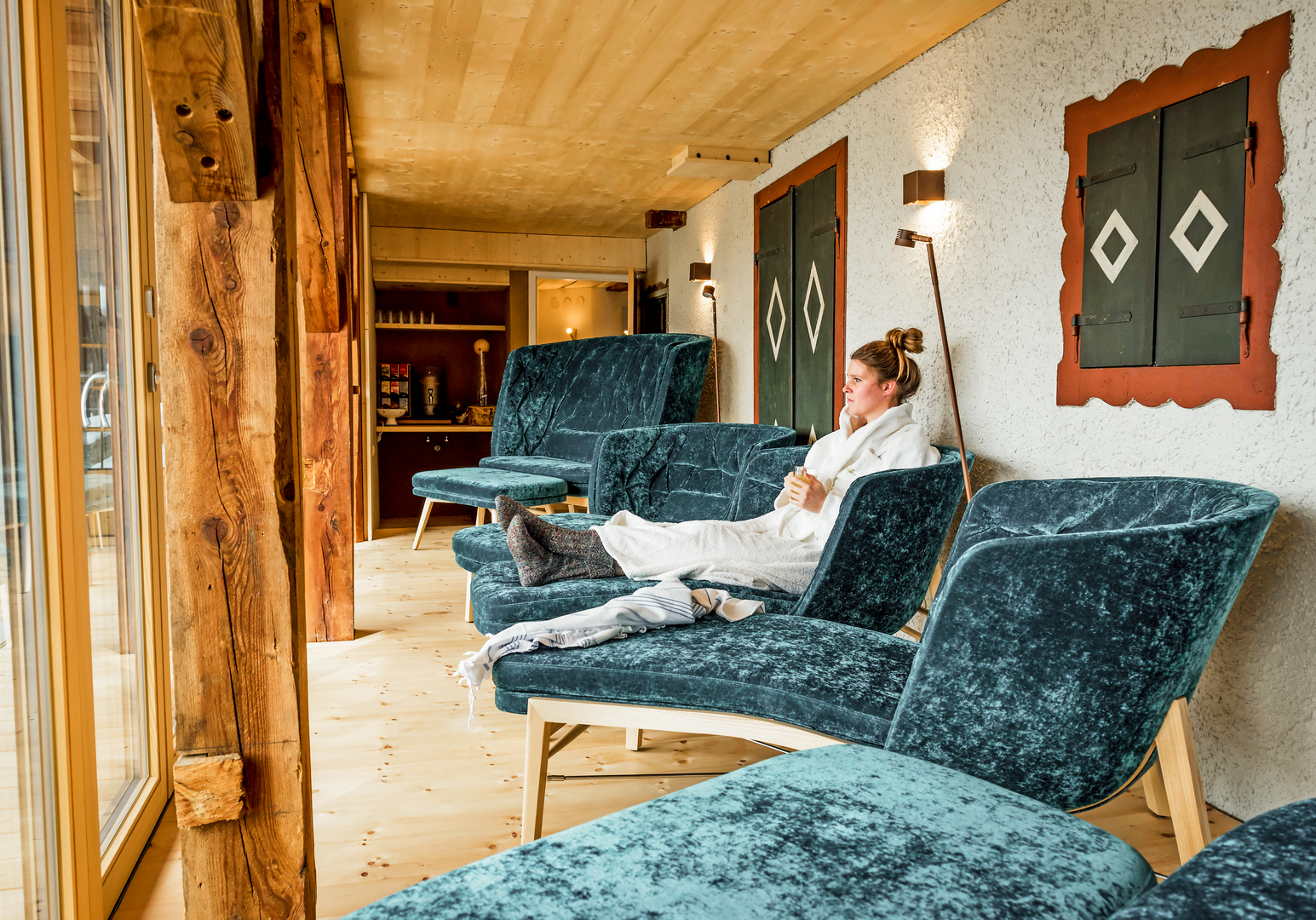 Gemütlicher Ruheraum mit Liegen, Holzverkleidung und Blick ins Freie.