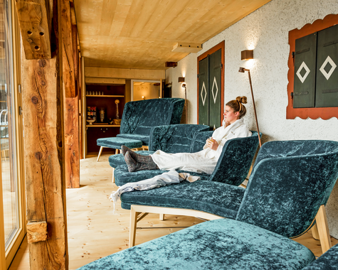 Gemütlicher Ruheraum mit Liegen, Holzverkleidung und Blick ins Freie.