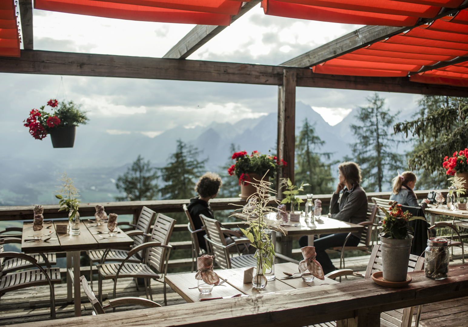 Sonnenterrasse mit gedeckten Tischen und Panoramablick auf die Berglandschaft.
