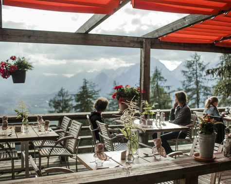 Sonnenterrasse mit gedeckten Tischen und Panoramablick auf die Berglandschaft.