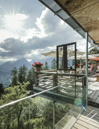 Restaurantterrasse mit Glasfronten und weitem Ausblick auf Berge und Täler.