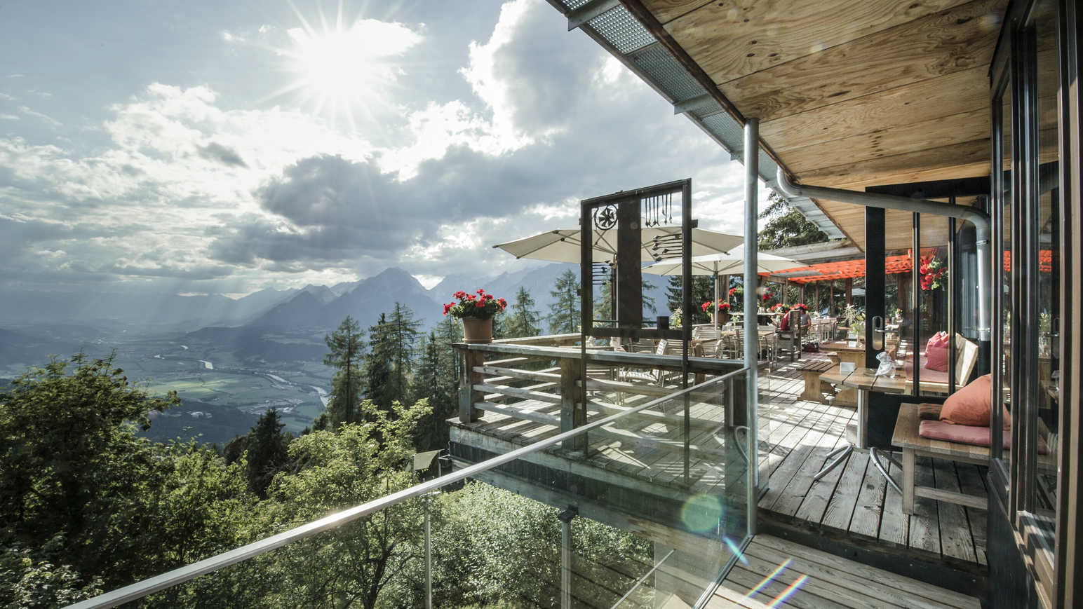 Restaurantterrasse mit Glasfronten und weitem Ausblick auf Berge und Täler.