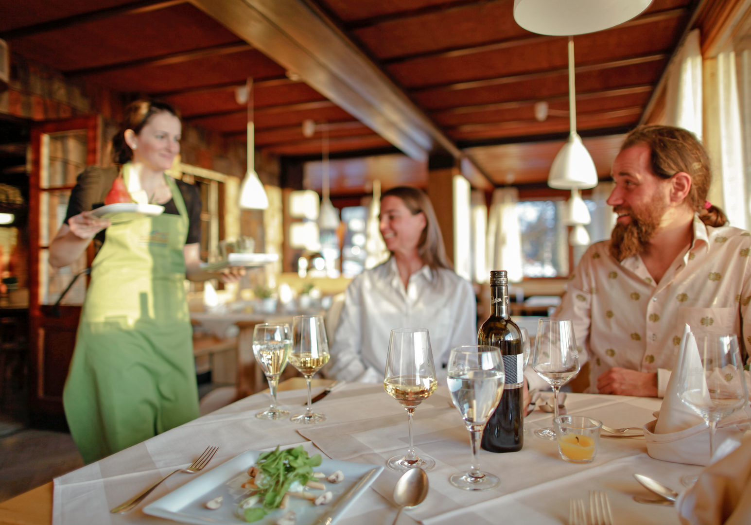 Familie genießt gemeinsam eine Mahlzeit in einem gemütlichen Restaurant mit Holzbalkendecke.