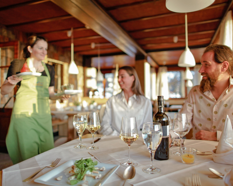 Familie genießt gemeinsam eine Mahlzeit in einem gemütlichen Restaurant mit Holzbalkendecke.