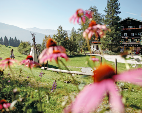 Blühender Garten mit Blick auf eine Berglandschaft und ein Hotelgebäude.