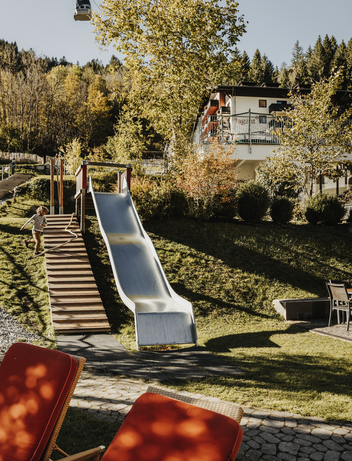 Spielplatz mit langer Rutsche und Treppenanlage im Freien.