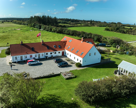 Bauernhofanlage aus der Luft mit mehreren Gebäuden, Innenhof und weitläufiger grüner Umgebung