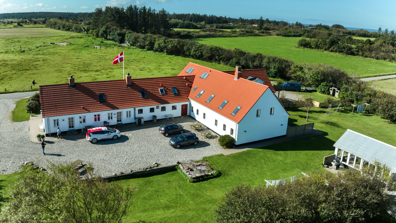 Bauernhofanlage aus der Luft mit mehreren Gebäuden, Innenhof und weitläufiger grüner Umgebung