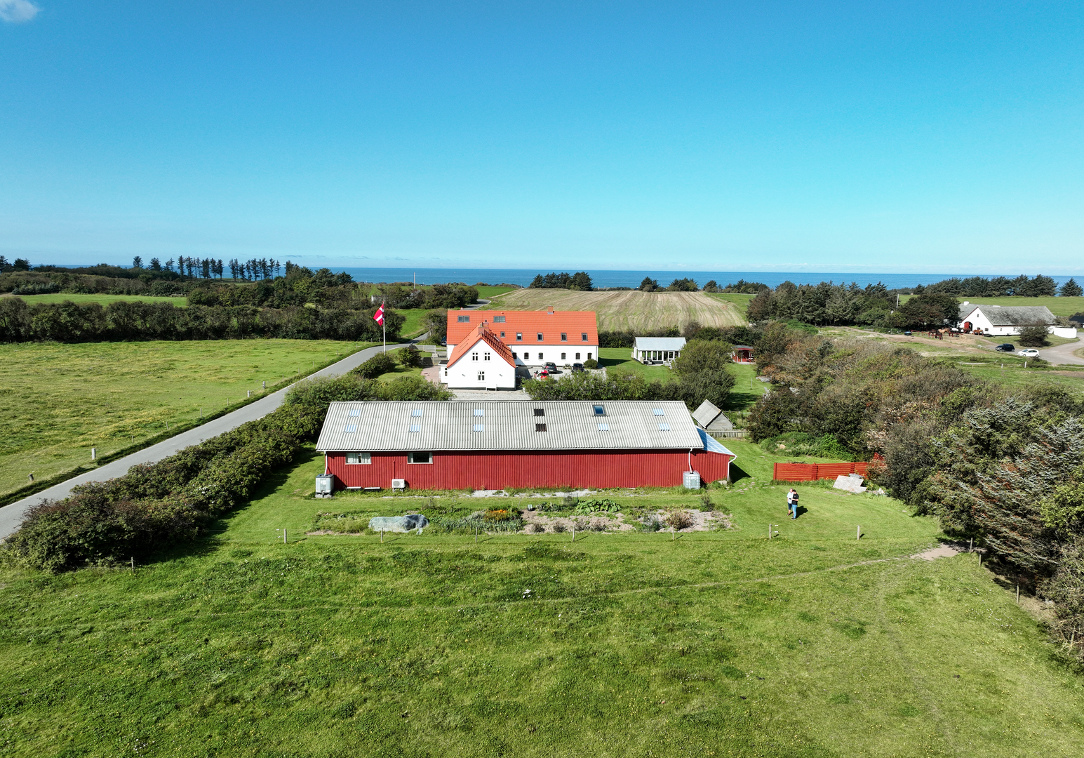 Hofgelände mit großem Gebäude und Scheune, umgeben von Wiesen und Hecken, aus der Vogelperspektive