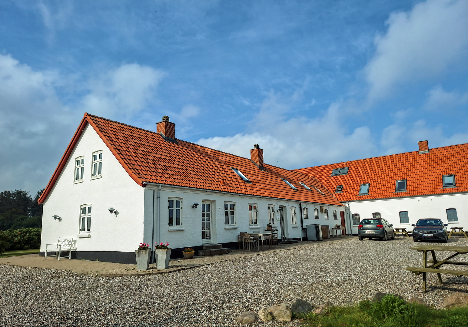 Langes Bauernhaus mit rotem Ziegeldach und Innenhof in ländlicher Umgebung