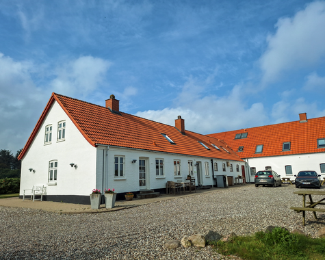 Langes Bauernhaus mit rotem Ziegeldach und Innenhof in ländlicher Umgebung