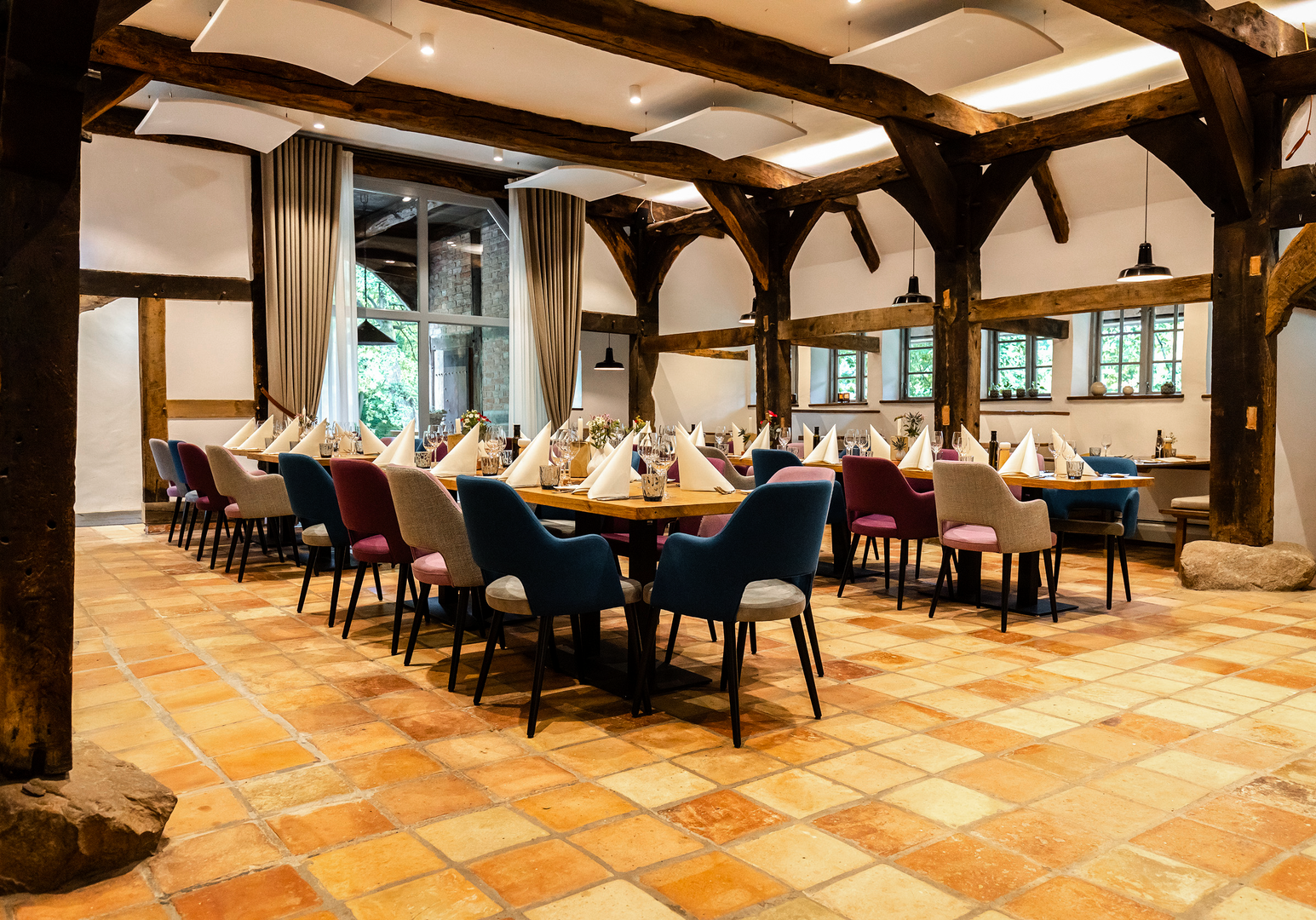 Großer Essbereich mit mehreren gedeckten Tischen, Holzbalken und Terrakottafliesen