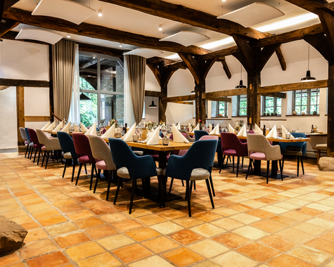 Großer Essbereich mit mehreren gedeckten Tischen, Holzbalken und Terrakottafliesen