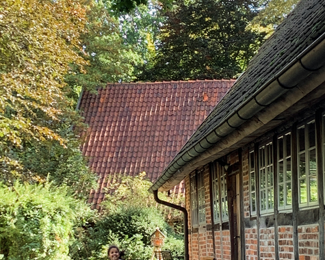 Idyllischer Innenhof mit Fachwerkgebäude, Bäumen und einem laufenden Kind 