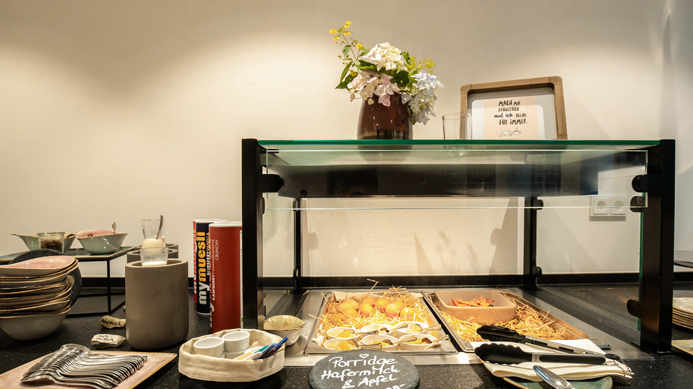 Frühstücksbuffet mit Geschirr, Brot und Blumen 