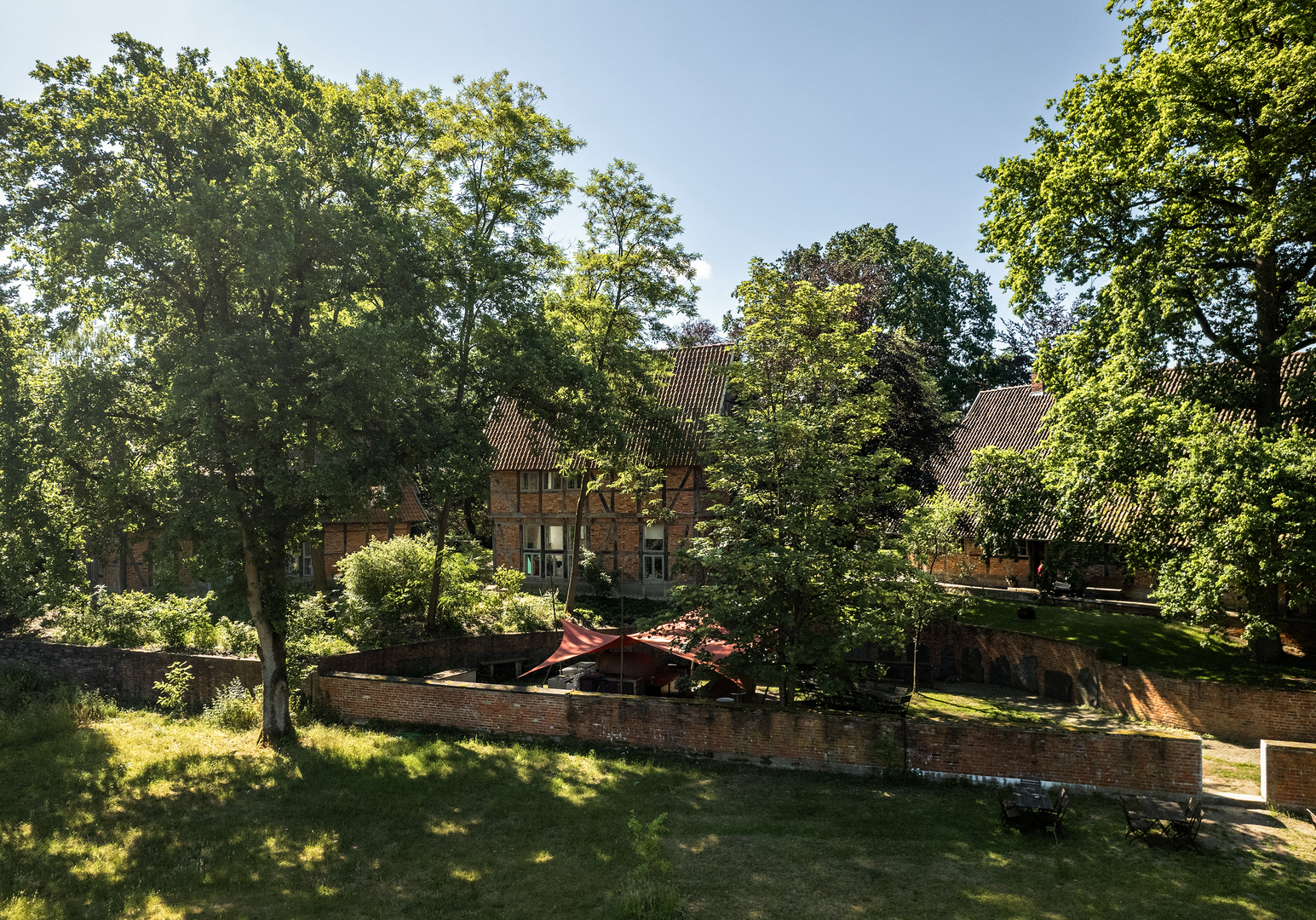 Großer Garten mit Fachwerkhaus, umgeben von hohen Bäumen