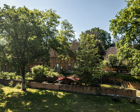 Großer Garten mit Fachwerkhaus, umgeben von hohen Bäumen