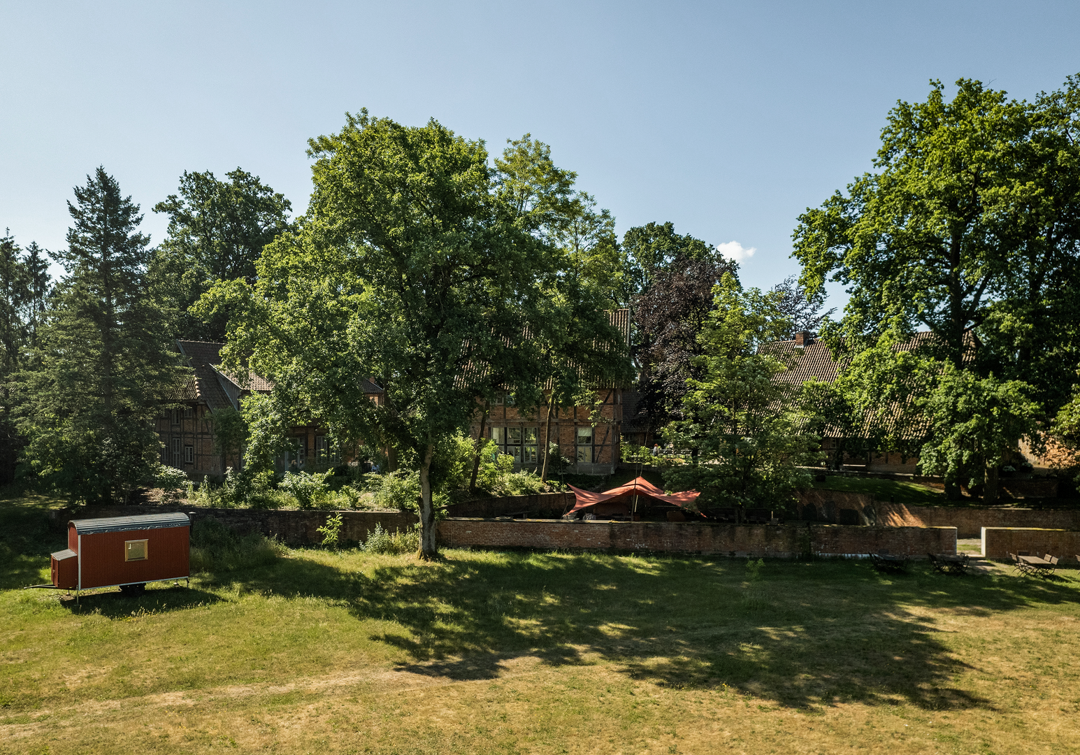 Weitläufige Wiese mit Bäumen und Spielbereich im Grünen