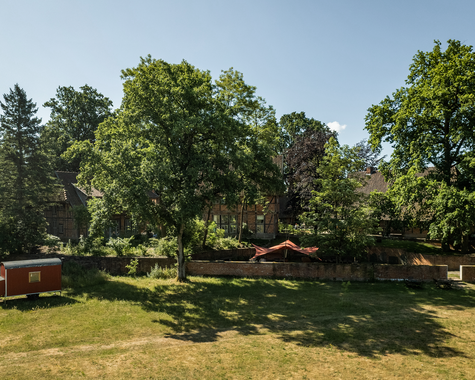 Weitläufige Wiese mit Bäumen und Spielbereich im Grünen