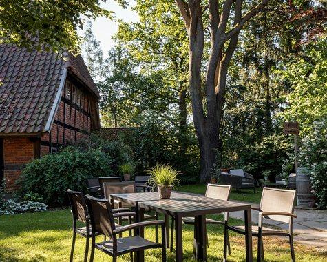 Garten mit Tisch und Stühlen unter einem Baum im Halbschatten