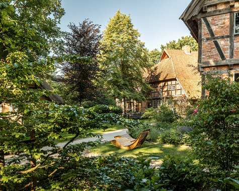 Üppiger Garten mit Liegestühlen und Fachwerkhaus im Hintergrund