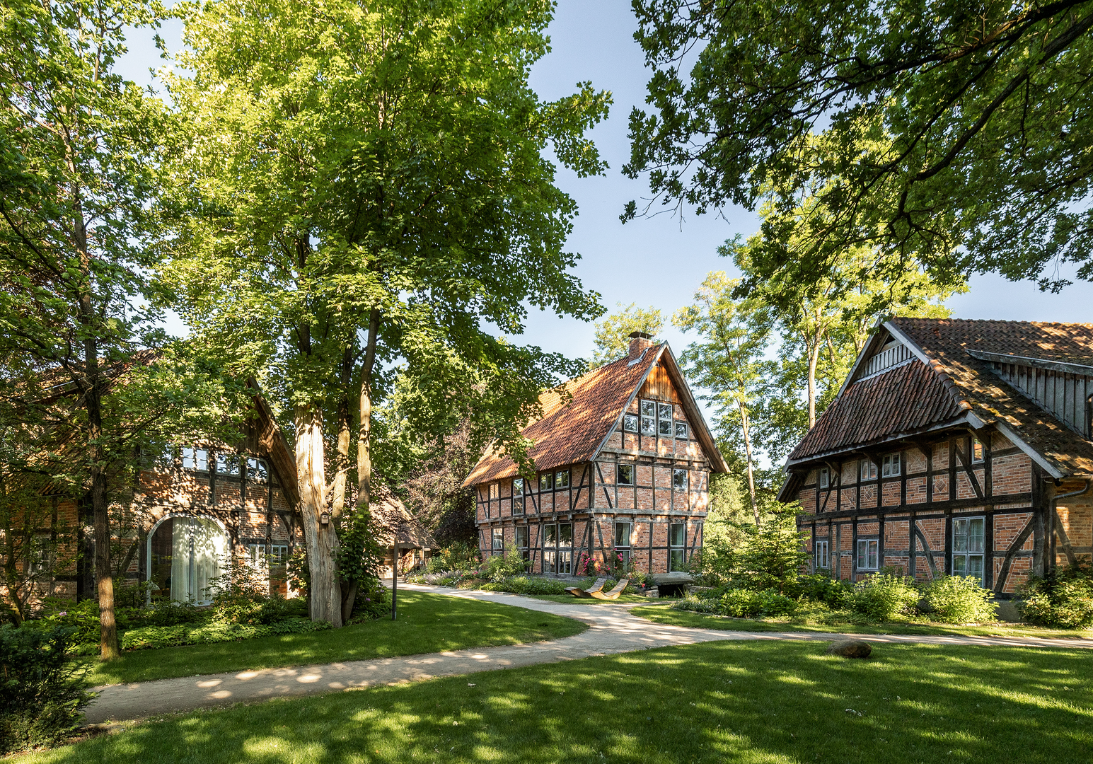 Fachwerkhäuser in einem gepflegten Garten mit großen Bäumen