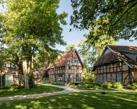 Fachwerkhäuser in einem gepflegten Garten mit großen Bäumen
