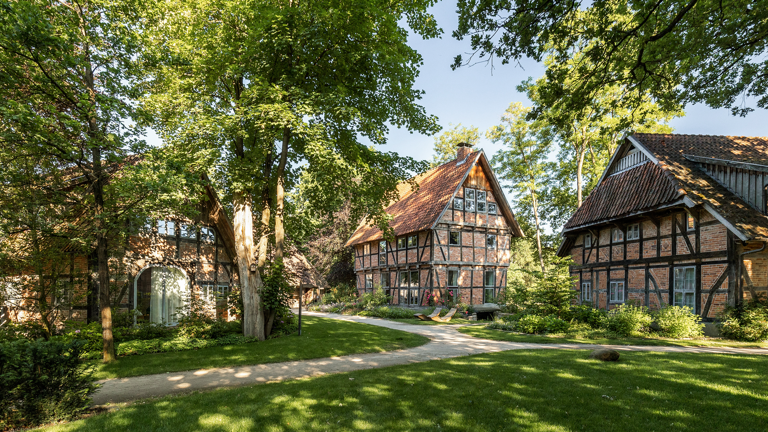 Fachwerkhäuser in einem gepflegten Garten mit großen Bäumen