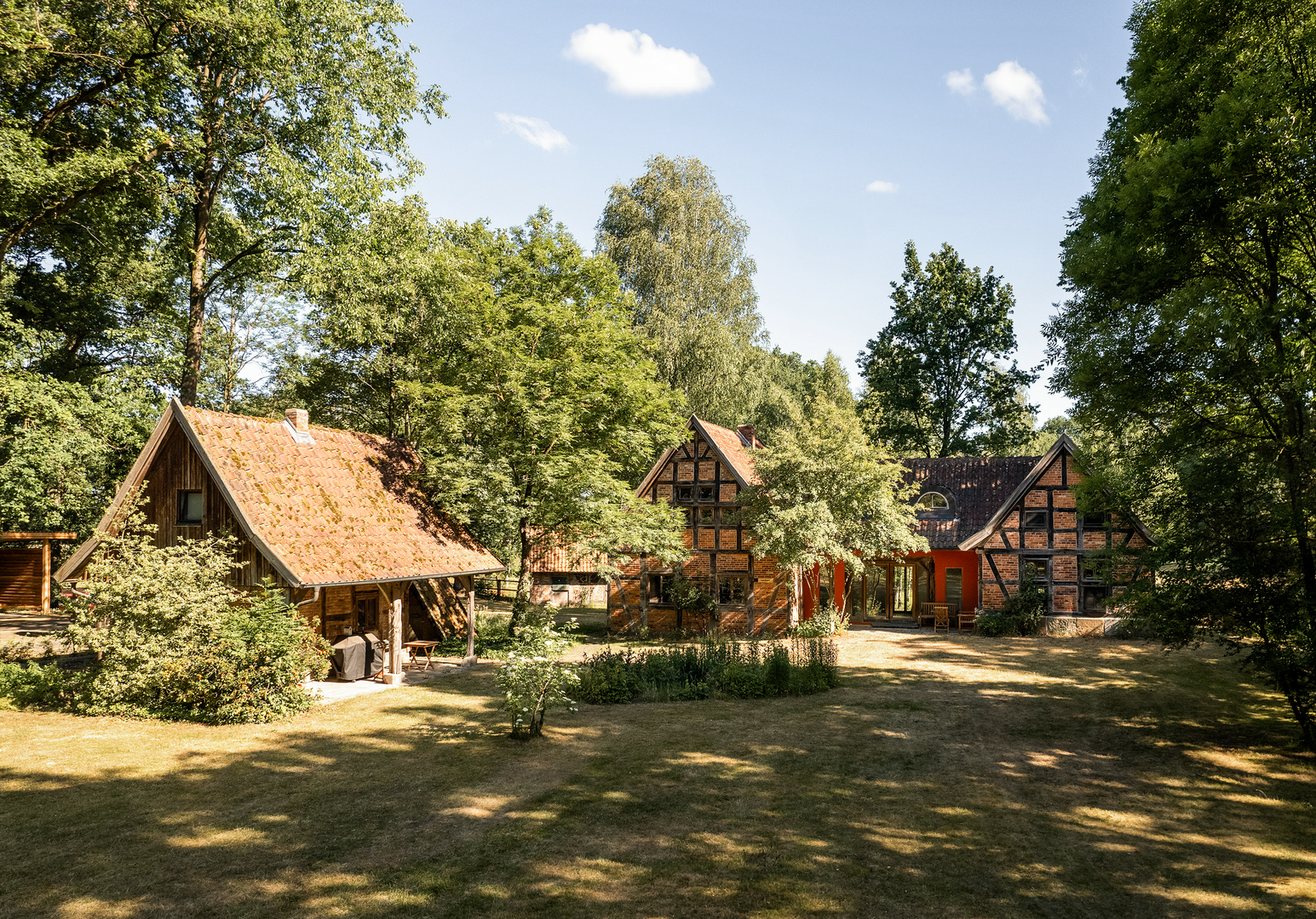 Innenhof mit mehreren Fachwerkhäusern und schattigem Baumbestand