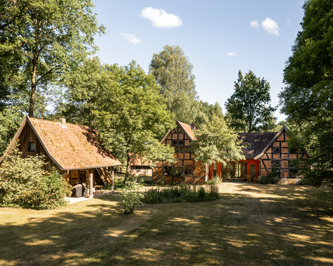 Innenhof mit mehreren Fachwerkhäusern und schattigem Baumbestand