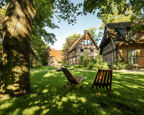 Garten mit Liegestühlen unter Bäumen vor Fachwerkgebäuden