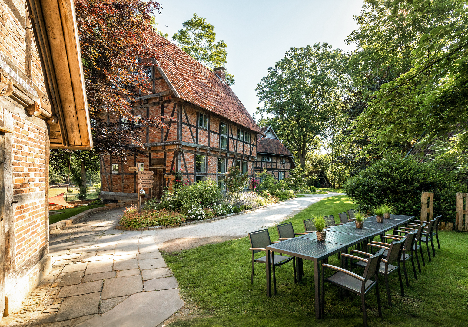 Außenbereich mit langen Tischen vor Fachwerkhäusern im Garten