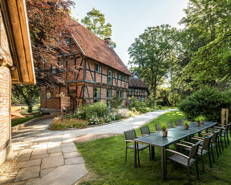 Außenbereich mit langen Tischen vor Fachwerkhäusern im Garten