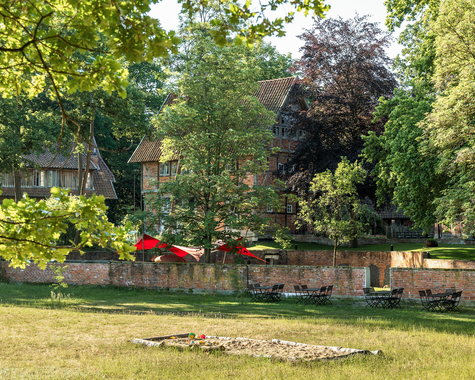 Garten mir Bänken und einer Sandkiste und einer Mauer mit Haus im Hintergrund