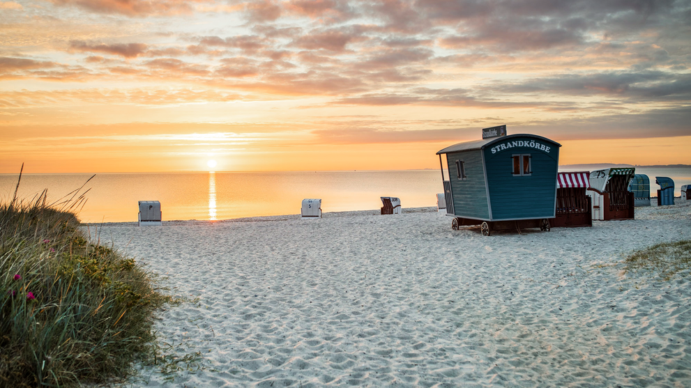 Strand mit Strandkörben bei Sonnenuntergang und weitem Horizont
