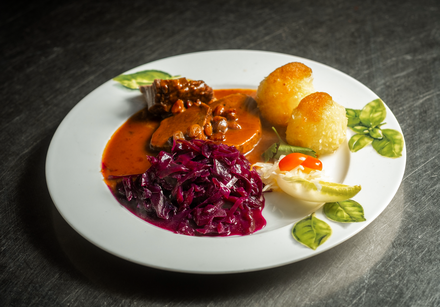 Teller mit Fleischgericht, Rotkohl und Kartoffeln angerichtet