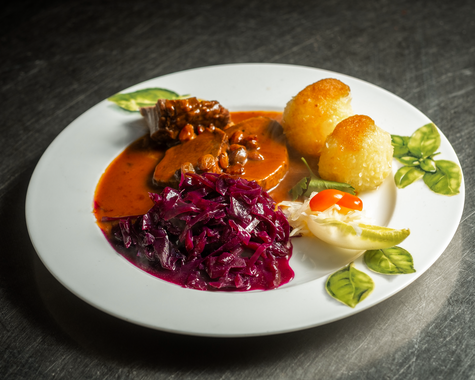 Teller mit Fleischgericht, Rotkohl und Kartoffeln angerichtet