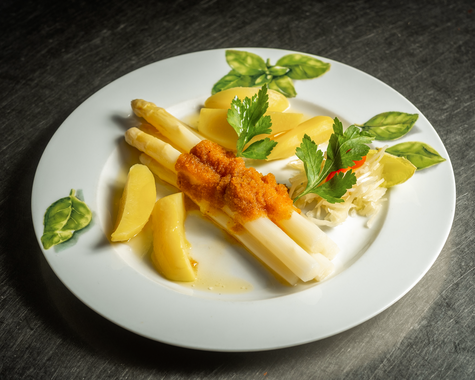 Spargelgericht mit Kartoffeln und Beilagen auf einem weißen Teller 