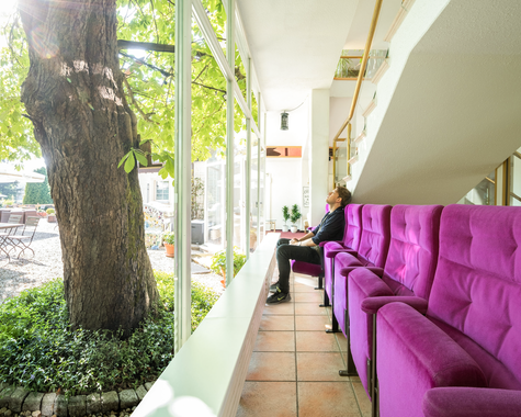 Veranda mit pinkfarbenen Sitzmöbeln und Blick ins Grüne