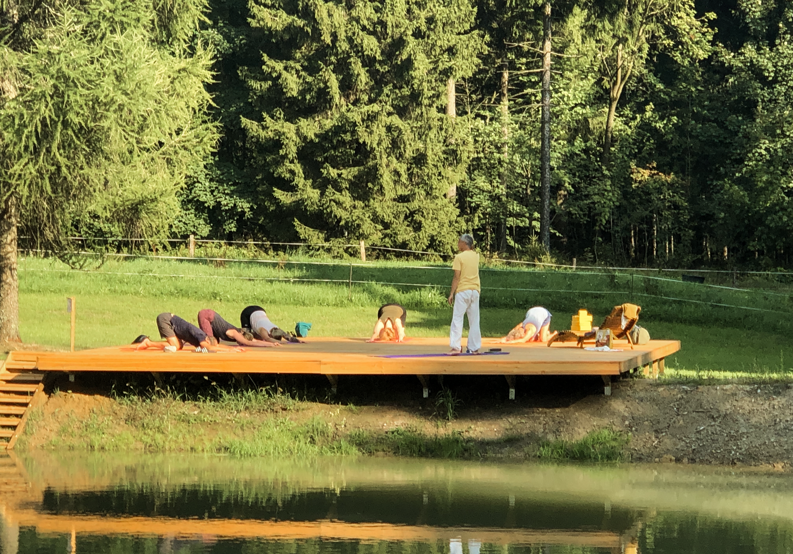 Menschen machen Yogaübungen auf dem Steg am ruhigen See