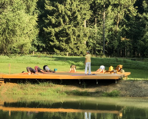 Menschen machen Yogaübungen auf dem Steg am ruhigen See