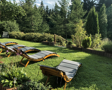 Liegestühle auf einer Wiese mit Blick auf eine grüne Hügellandschaft