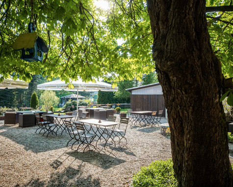 Schattiger Gartenbereich mit Sitzgelegenheiten unter einem großen Baum