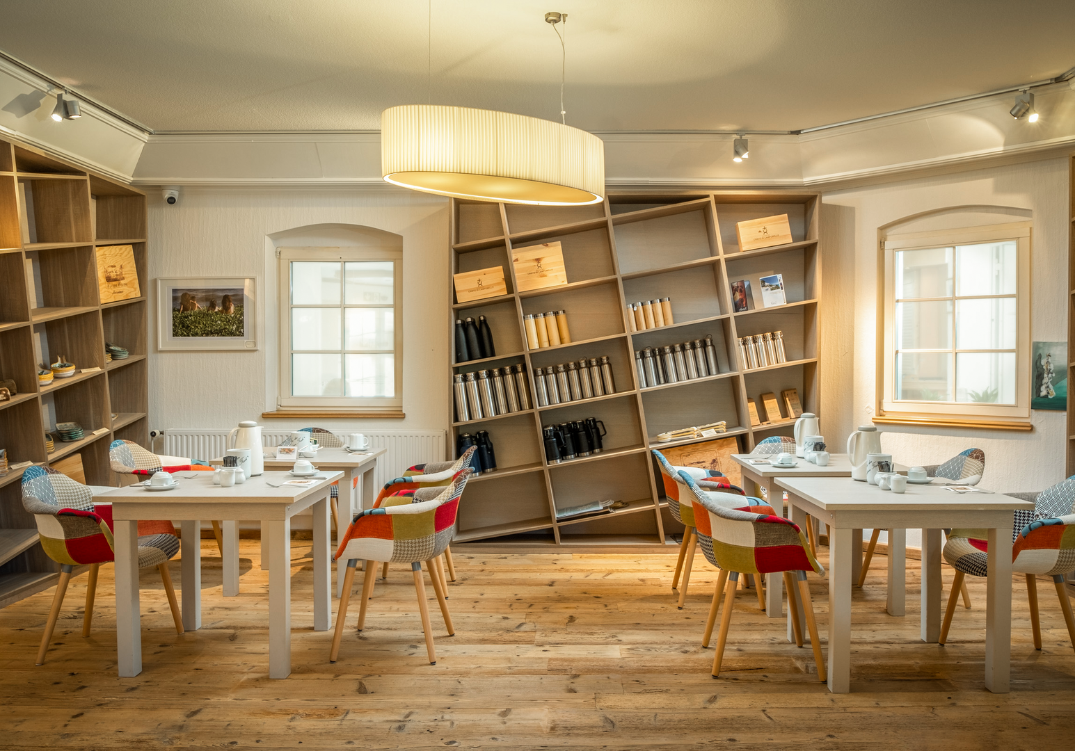 Heller Frühstücksraum mit Tischen, Stühlen und Bücherregalen