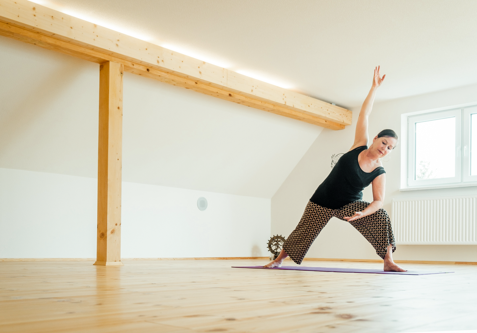 Frau macht eine Yoga-Übung in einem lichtdurchfluteten Raum